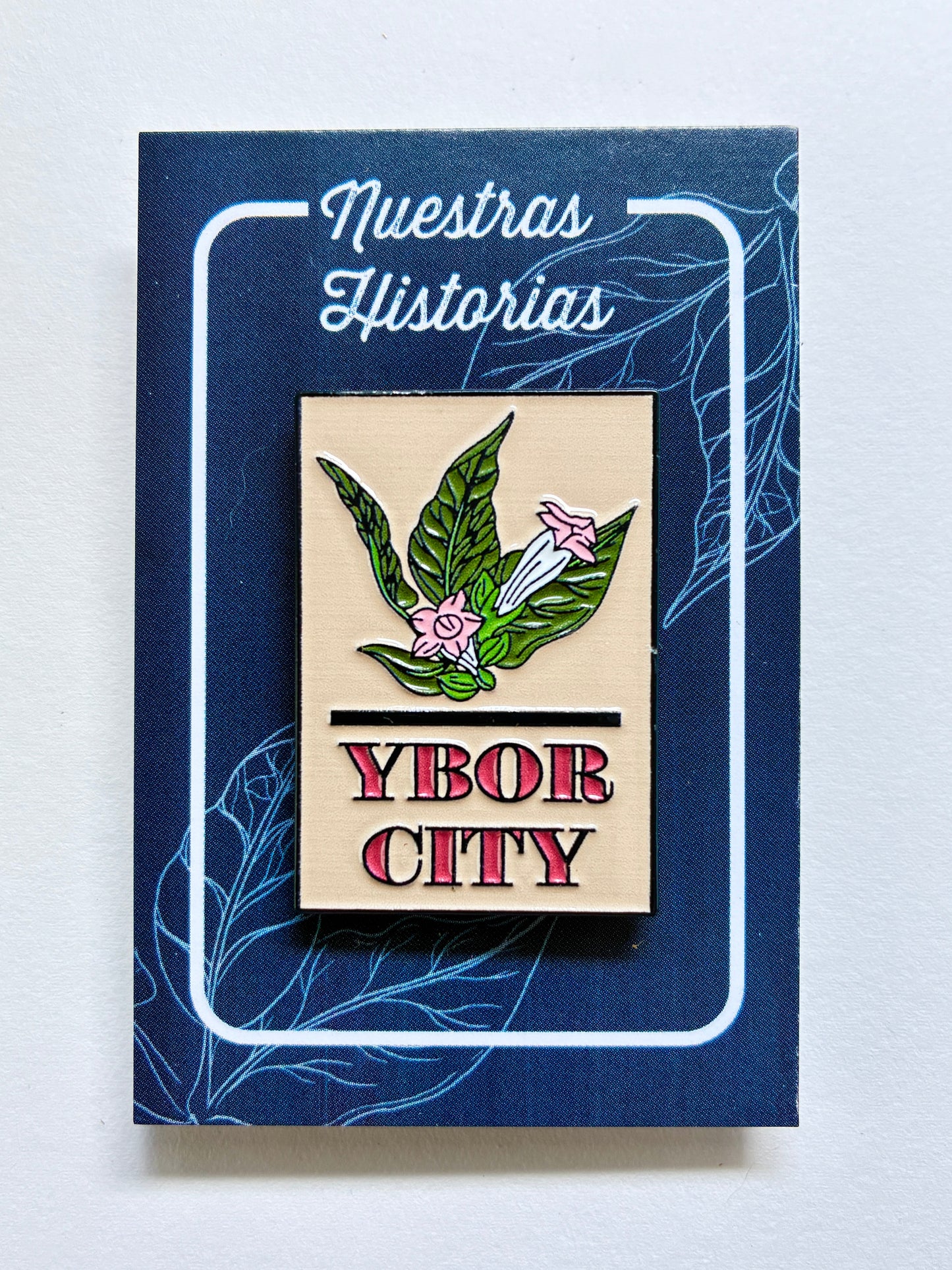 Enamel pin with tobacco leaf and flowers and the words Ybor City